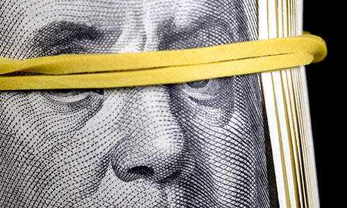 Ben Franklin image from hundred dollar bill with eyes covered by yellow elastic blindfold