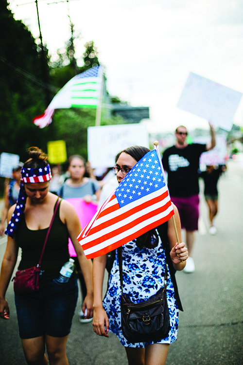 young people marching in demonstration with American flags and signs