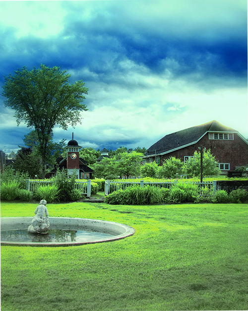 Goddard College campus with cloudy sky and cherub fountain