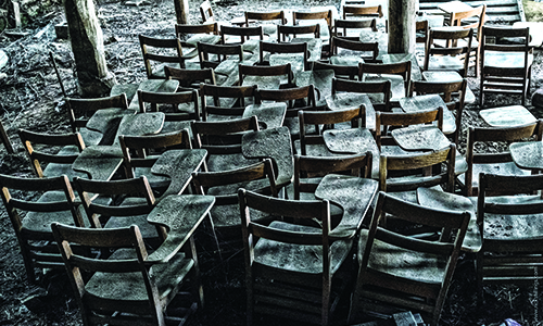 A cluster of old desks with layers of dust and debris.